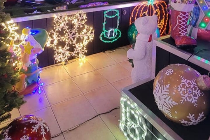 Festive outdoor Christmas lighting display with a glowing snowflake, top hat, polar bear, and red boot. Ornate light-covered ornaments add to the holiday home's cheerful ambiance.
