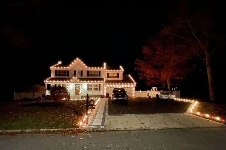 House decorated with Christmas lighting; white lights outline the roof, walkway, and landscaping, creating a warm, festive holiday home.