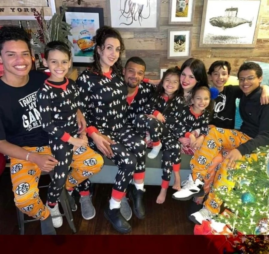 A large family gathers for a festive holiday photo, many wearing matching black and white pajamas with orange pants featuring Japanese symbols. The "About" this family is their love and togetherness.
