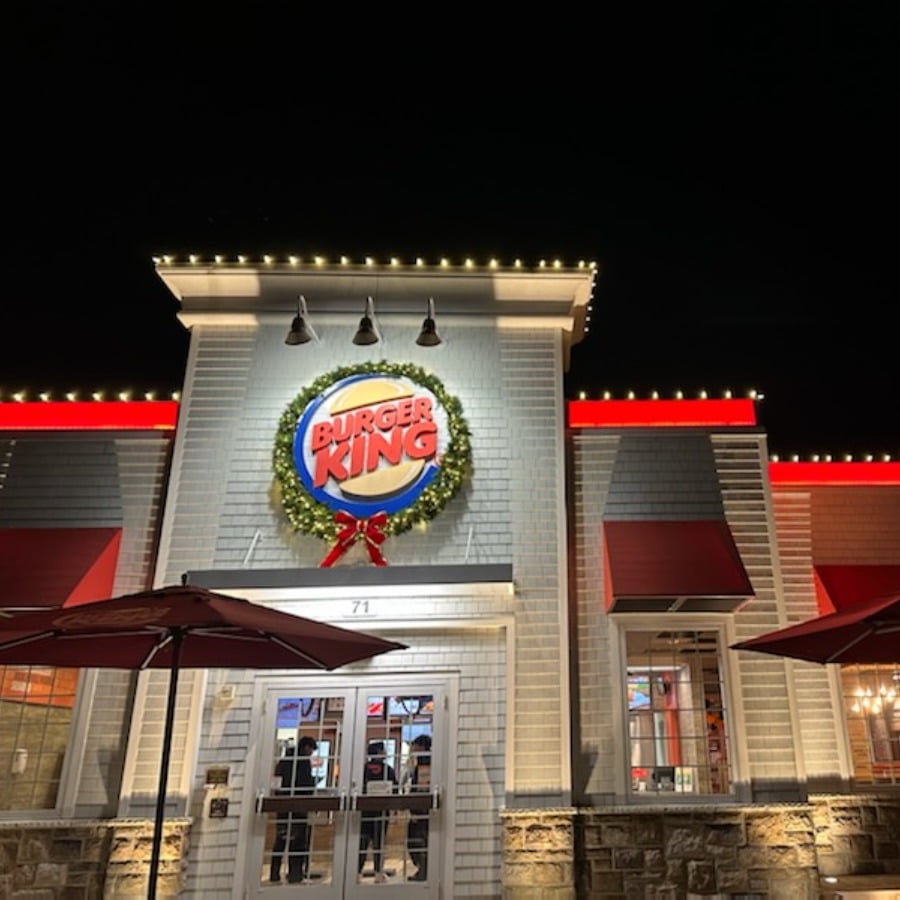 Burger King restaurant at night decorated with Commercial Holiday Lighting. A festive wreath with the Burger King logo hangs above the entrance.