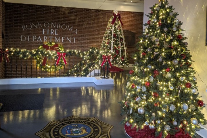 Christmas lighting decorates the Ronkonkoma Fire Department lobby. A Christmas tree, lighted garland, and a decorative tree frame create a festive scene.